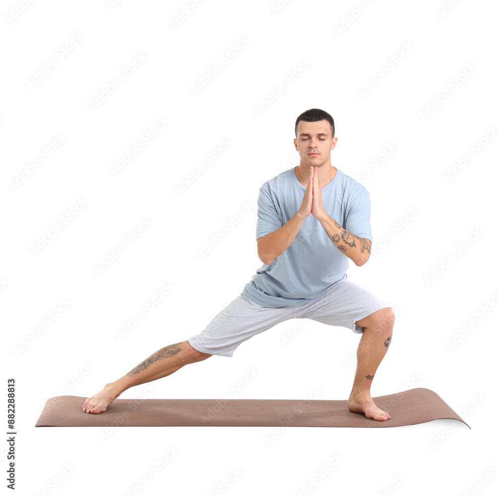 Young man doing yoga on mat against white background