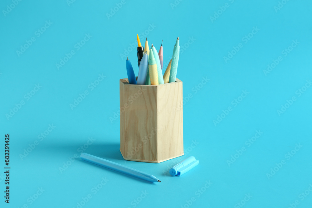 Wooden holder with pens on blue background