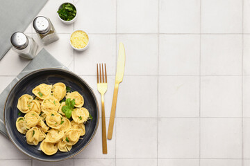 Wall Mural - Bowl of boiled dumplings with cheese and basil on white tile background