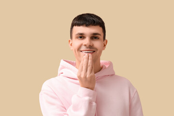 Wall Mural - Young deaf mute man using sign language on beige background