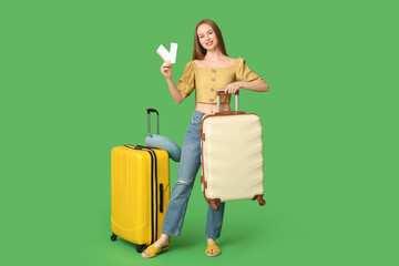 Sticker - Happy young woman with luggage and tickets on green background. Travel concept