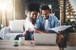 © peopleimages.com - Couple, laptop and happy with documents for bills on sofa with planning taxes or loan application success in home. Black people, tech or pointing to paperwork for mortgage contract or insurance admin