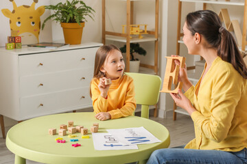 Poster - Female speech therapist with cute little girl pronouncing letter E in office