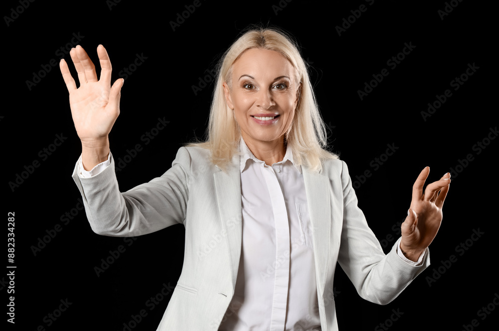 Mature businesswoman using virtual screen on black background