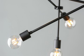 A close-up of a contemporary black pendant light fixture with three bulbs. The fixture features geometric shapes and a minimalist design