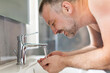 © Home-stock - Male morning routine. Man with naked torso washing up his face with water standing near sink tap, doing daily routine, side view