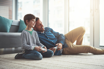 Wall Mural - Man, video game and kid with smile on floor for entertainment, care or fun competition together. Family, father and son with controller in living room for support, love or learning of esports at home