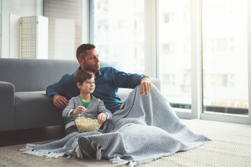 Poster - Popcorn, relax and dad watching tv with child on floor in living room at family home. Blanket, bonding and father with kid for streaming movie, film or show with snack in lounge at house in Canada.