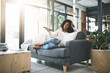 © peopleimages.com - Relax, smile and television with woman streaming on sofa in living room of home for break or time off. Comfortable, video and watching tv with happy person in apartment with subscription service