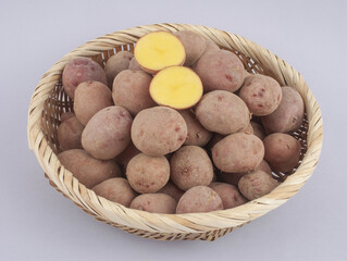 Wall Mural - Close-up of stacked raw potatos with two sections on bamboo basket and white floor, South Korea
