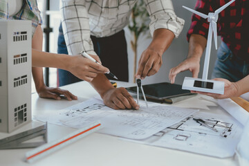 Wall Mural - architects are designing a building project together at work with blueprints and a model of a buildi