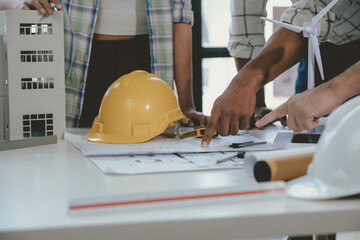 Wall Mural - architects are discussing a new project using a model house and blueprints on a table, with a focus 