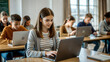© NewFresh  - Teenage girl using laptop in classroom with other students in the background