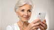 © NewFresh  - Closeup portrait of smiling senior woman using mobile phone at home.