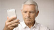 © NewFresh  - Senior man using mobile phone, focus on face. Closeup portrait of senior man using smartphone, blurred background