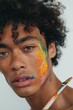 © Enigma - Young artist with curly hair and colorful paint splatters, holding a paintbrush, expressing creativity in a self-portrait