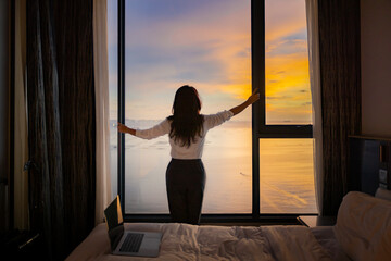 Confident businesswoman work remote on laptop while enjoying panoramic beach landscape. Inspire tropical beach seascape horizon. Orange and golden sunset sky calmness tranquil relaxing sunlight.

