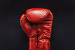 © Firn - Bright red boxing glove on black studio background