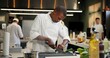 © peopleimages.com - Black man, chef and serious with cutting vegetables in kitchen at restaurant for fine dining, meal or creativity. Male employee, professional or cooker with food for culinary, hospitality or catering