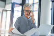 © peopleimages.com - Woman, phone call and paperwork with laptop in office for investment, plan or report on client finance. Mature financial advisor, work and consulting with tech for foreign exchange, trading or update