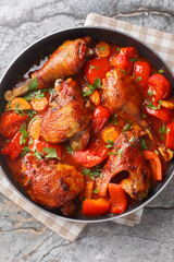 Canvas Print - Homemade rooster cooked with vegetables in tomato sauce close-up in a pan on the table. Vertical top view from above