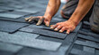 © Hound - A roofer is laying black shingle on the roof of an old house