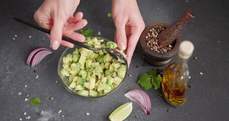 Wall Mural - Woman mixing Chopped ingredients in a glass bowl - avocado, pepper and cooking olive oil