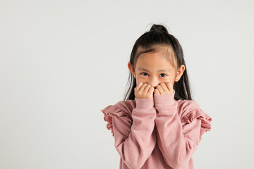 Wall Mural - Asian portrait cute young kid girl standing amazed, shocked afraid mouth covered gesturing hand palms looking camera, studio shot isolated on white background, Thai kindergarten child scared