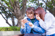 © Daisuke Morita - スマートフォンで面白い写真を友人に見せている若い日本人女性