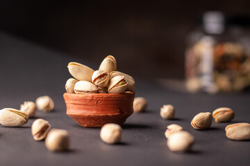 Pistachio nuts in wooden bowl on black background. Pistachios are rich in nutrients and good source of protein, fiber, and antioxidants. Healthy food concept. Flat layout.