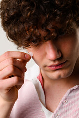 using acne pimple patch to clean the face from zits. young man uses acne stickers as bandage not to 