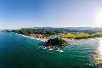 Summer and afternoon view of sea wave on seaside rock and Deokbongsan Mountain against Maeupcheon Stream and Beach at Deoksan-ri near Samcheok-si, South Korea
