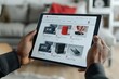 © Kanin - Person shopping online with a tablet, browsing various electronic products in a modern living room setting.