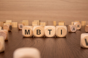 Sticker - four wooden cubes with the text 'MBTI on a brown background. Myers-Briggs Type Indicator - MBTI - in corporate settings