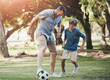 © Daniel L�/peopleimages.com - Nature, football and father playing with child in outdoor park practicing for sports game together. Fun, bonding and dad kicking soccer ball with boy kid for training in field or garden in Canada.