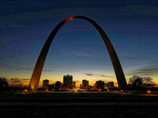 Wall Mural - A large archway with a city in the background. The archway is lit up at night