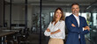 © Stock 4 You - Banner portrait of smiling mature Latin or Indian leader man and European confident woman standing arms crossed in office. Two diverse colleagues, group team of confident professional business people