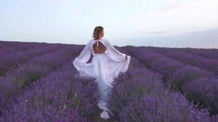 Canvas Print - A woman in a white dress is standing in a field of purple flowers