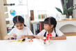 © K2L Family - two sibling Asian girl playing windmill stacks at home