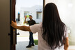 © AntonioDiaz - Woman greets her neighbor at the front door as they wave from the driveway