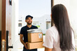 © AntonioDiaz - Smiling delivery man delivers packages to a customer's home, showcasing excellent service and efficient courier logistics