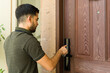 © AntonioDiaz - Young man using a smart lock with digital touchscreen and entering his passcode onto a keypad to access his house