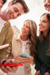 © CarlosBarquero - Vertical. Low angle group of young happy people standing in circle, laughing and sharing cell phone. Cheerful friends using mobile smiling having fun together outdoors