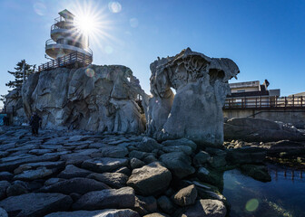 Jumunjin, Gangneung-si, Gangwon-do, South Korea - December 2, 2023: Winter and afternoon view of strange rocks and sea pool against lighthouse and sunlight in the sky at Sonbawi Park
