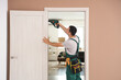 © Pixel-Shot - Male worker with electric drill repairing door at home