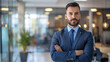 © Elbitaso - Latin mature businessman standing alone in an office with a blurred background.