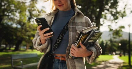 Aufkleber - Happy woman, student and walking with phone or books in park for communicatio, social media or reading news. Female person on mobile smartphone for online browsing, learning or education in nature