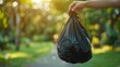 © pornsawan - Hand holding garbage black bag putting in to trash,Garbage bag in a trash bin,waste management and recycling concept,black plastic bags,Waiting for the rubbish keeper officers to take them away.