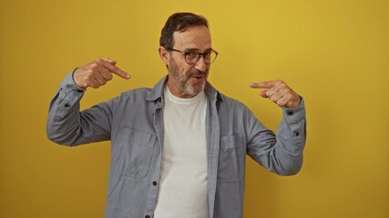 Poster - Hispanic man, middle-age individual wearing glasses, standing and pointing with a confident finger, happy and proud self over an isolated yellow background