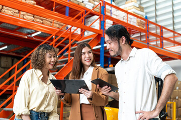 Diverse team discusses logistics in a warehouse, each holding a tablet, highlighting collaboration and technology in inventory management.